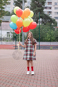 穿着彩色棕色礼服的迷人少女 带着一帮多彩气球 女学生飞行孩子自由惊喜服装生日裙子派对休闲跑步图片