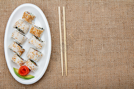 Uramaki 寿司卷 配有鳄梨和陶瓷板上的红鱼美食食物盘子白色海苔黑色红色海鲜海藻麻布图片