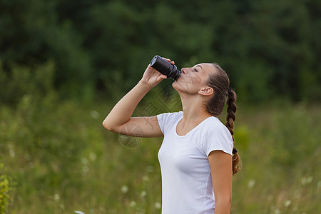 妇女用塑料瓶水喝的饮用水青年享受公园瓶子锻炼长发跑步力量活动毛巾图片