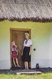 母亲和女儿都站在离家门近的门边文化房子民族微笑裙子传统父母服装历史家庭图片