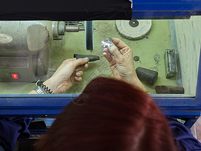 一名身份不明的成年妇女 在她的珠宝车间用安全箱打磨机工作 (a)图片