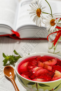 碗里的樱桃果冻和草莓片 还有背景的书图片