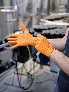 一位工人在酿酒厂戴上乳胶手套的垂直照片图片