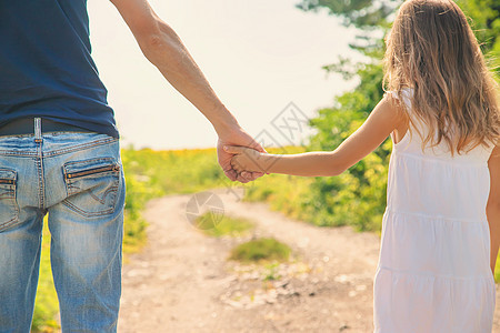 父亲和女儿手牵手走路 有选择地集中注意力友谊童年太阳手臂晴天婴儿父母女性海滩爸爸图片