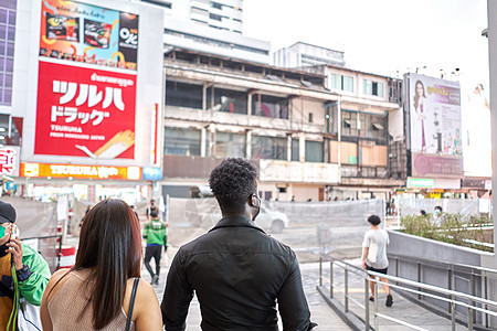 两名多种族朋友背着广告海报在商场外散步的背后背景图片