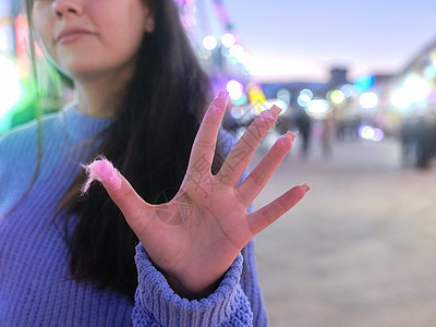 女人用棉花糖的痕迹展示手掌 在集市上粘着它背景图片
