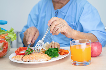 亚洲年长或年长的老妇人病人坐在医院的床上饿着肚子吃鲑鱼排早餐和蔬菜健康食品退休托盘女性医生男人老年护士女士营养卫生图片