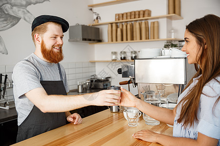 咖啡经营理念年轻英俊的咖啡师在现代咖啡店里说话 并为美丽的白人顾客送走热咖啡服务女士杯子夫妻服务员商业成人店铺餐厅员工图片
