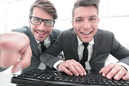 两位商务人士看镜头 用一只手指露面相机食指快乐眼镜男性微笑白色男朋友键盘夫妻图片