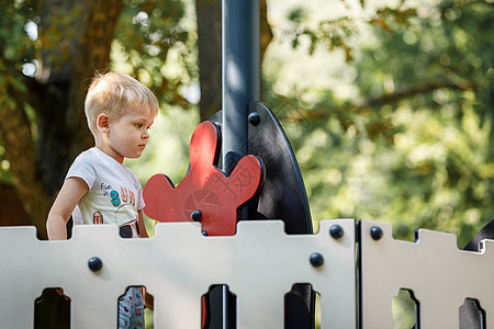 小男孩在儿童游乐场充满信心地旋转着玩具船的舵图片