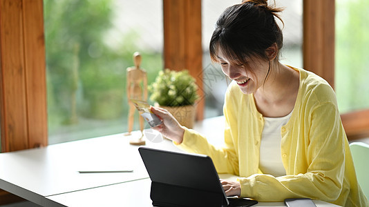 拥有信用卡和网上购物 在电脑平板电脑上付费的亚洲妇女 她们非常愉快图片