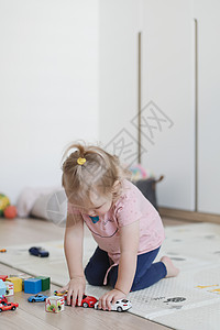 一个有趣的小女孩玩 与立方体和玩具 在地板上在托儿所图片