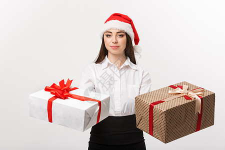 圣诞节概念  年轻快乐的白人女商务人士戴着圣诞老人的帽子 可以选择礼品盒给相机 旁边有复印空间丈夫生意人老板红领巾夫妻花费女性灰图片