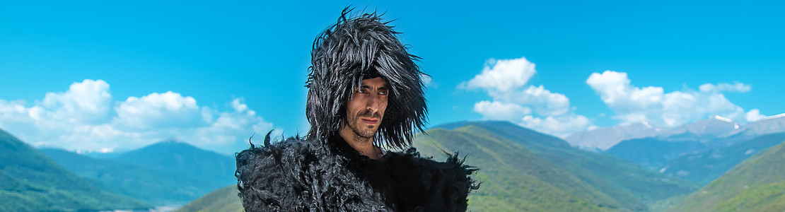 一个身戴帽子的格鲁吉亚人 在山顶和天空的背景之下 有选择地专注披风毛毡纪念品旅行传统文化头饰木瓜戏服男人图片