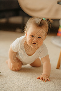 一名7个月的女孩跪在地毯上 用一只手抓着她图片