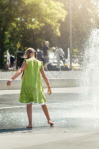 在公园喷泉前穿绿衣的赤脚女孩 高水流 在炎热的夏季日子里给儿童带来乐趣城市娱乐幸福阳光游戏青少年运动孩子溅板活动图片