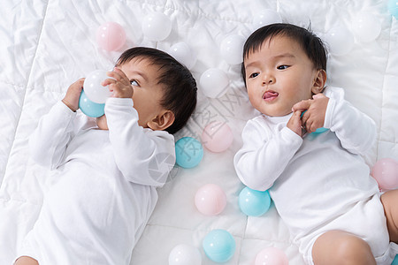 快乐的双生婴儿在床上玩彩球男生卧室乐趣女性婴儿幸福兄弟女士微笑家庭图片
