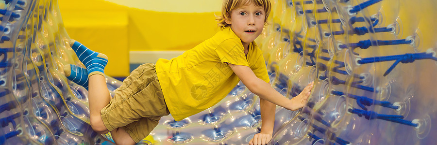 可爱的小男孩 在Zorb玩一个滚动塑料圆筒环 中间有一个洞 内门银行家图片