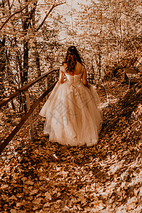 穿着白婚礼服的新娘 在秋森林中走过落橙色树叶橙子婚姻裙子女孩女士婚礼奢华阳光头发童话图片