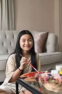 坐在客厅地板上的可爱的亚裔女孩 画着水彩画的照片图片