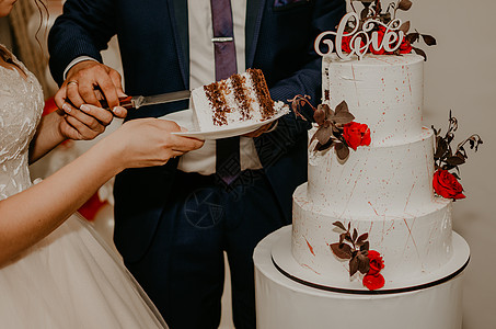 新郎和新娘在婚礼上 切了他们的大 多层白蛋糕的味道 它从互相喂养裙子桌子庆典接待巧克力男人甜点结婚夫妻新婚图片