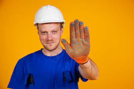 男性工人显示停止手势 工作服和防护头盔的工人用戴手套的手展示停止手势图片