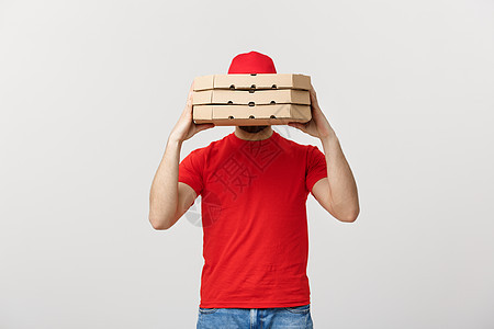 一个快递员藏在他携带的 一大堆披萨盒后面 被灰色背景隔绝男人工人红色工作白色送货邮递员帽子职业快乐图片