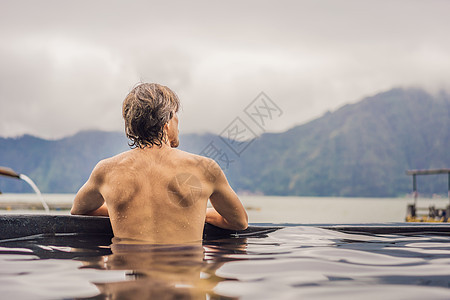 在温泉游泳池中放松的人 享受洗澡的年轻人在蓝色水礁湖中放松 旅游景点是溪流肩膀水池淋浴身体男人活动旅行男性蒸汽图片