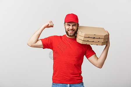 交付概念强健英俊送货员的肖像 他伸展肌肉并拿着披萨盒包 孤立在灰色工作室背景上 复制空间微笑导游柔性盒子衬衫船运食物男人包装邮递图片