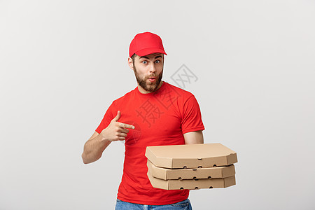 交付概念 英俊的caucasian披萨送货员用手指指着 在灰色背景上孤立无援食物工作盒子胡须工人男人微笑职业幸福服务图片
