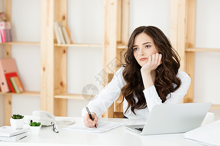 在明亮的现代办公室室内装有笔记本和文件的年轻漂亮商业女青年思维压力技术工作互联网电脑经理管理人员桌子女士图片