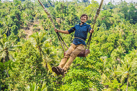 年轻人在印度尼西亚巴厘岛的丛林雨林中荡秋千 在热带摇摆 秋千巴厘岛的潮流男人绳索女孩悬崖高度闲暇太阳冒险天空飞行图片