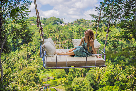 年轻女子在印度尼西亚巴厘岛的丛林雨林中荡秋千 在热带摇摆 秋千巴厘岛的潮流青少年冒险座位绳索假期天空荒野旅游乐趣高度图片