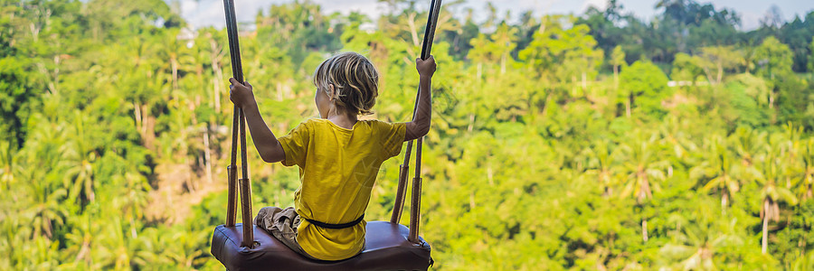 横幅 长格式小男孩在印度尼西亚巴厘岛的丛林雨林中荡秋千 在热带摇摆 秋千  巴厘岛的趋势 带着孩子旅行的概念 带孩子怎么办 儿童图片