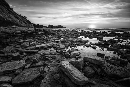 一个惊人的日出 在岩石海岸海 黑色和白色的海图片