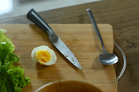 上面是煮鸡蛋 刀子和厨房木制桌上的新鲜生菜图片