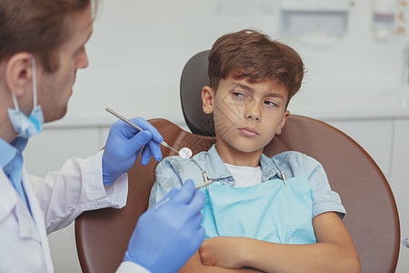 迷人的年轻男孩在牙医处接受牙齿检查医生考试预防病人保健职业矫正痛苦男人孩子图片