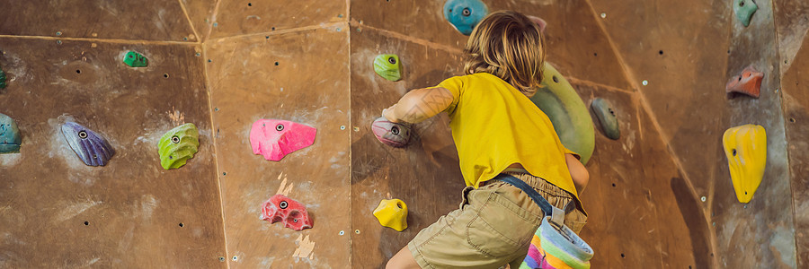 小男孩穿特别靴子爬岩墙 室内银行 长期的FormAT挑战青年公园安全活动运动格式登山者冒险男性图片