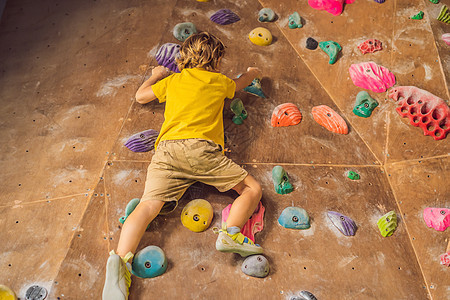 小男孩穿特别靴子在石墙上爬孩子岩石男生绳索男人登山者挑战操场活力风险图片