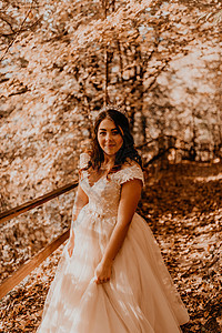 穿着白婚礼服的新娘 在秋森林中走过落橙色树叶女孩头发灌木丛跑步裙子公主阳光女士森林童话背景图片