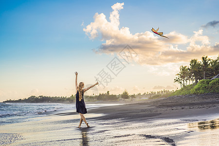 年轻女人在海滩上放风筝 梦想 愿望 未来计划蓝色太阳微笑成人热带喜悦天空孩子活力活动图片