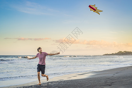 青年男子在海滩日落时放风筝闲暇天空运动娱乐喜悦玩具蓝色女士行动活动图片