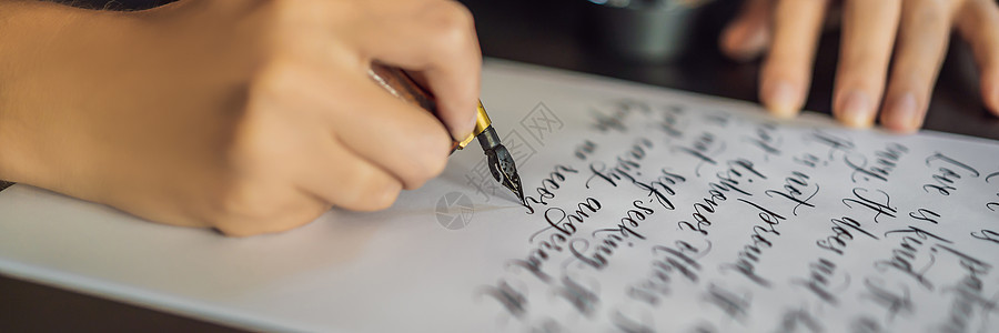 横幅 长格式书法家的手在白纸上写下短语 关于爱的圣经短语 刻有装饰性装饰字母 书法 平面设计 刻字 手写 创作概念艺术桌子卡片教图片