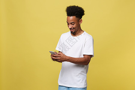 带着微笑和手机的非洲快乐男子 在黄色背景上孤立无援 笑声成人电话技术男人爆炸快乐商务短信细胞商业图片