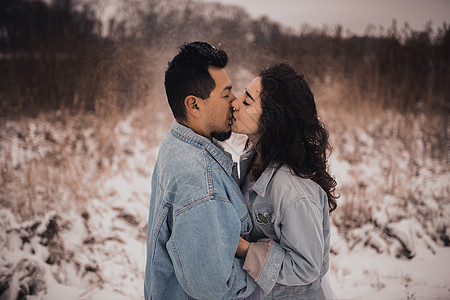 穿戴尼姆夹克的西西裔男人 身高超大 爱的女人 在冬天在雪中亲吻拥抱雪花森林女性恋人女士新娘喜悦男性幸福婚礼图片