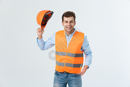 带着橙色背心的快乐年轻工匠肖像 在白色背景上被隔离建筑建设者职业帽子商业安全成人经理员工头盔图片