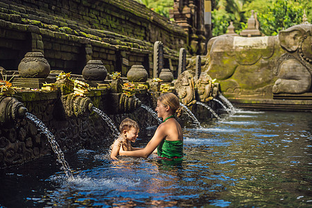 母亲和儿子在巴厘岛的圣泉水寺 寺庙大院由以圣泉水而闻名的 petirtaan 或沐浴结构组成建筑学纯化异国舞蹈岩石宗教地标传统水图片