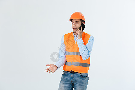 建筑工程师在移动电话上讲话 严重成年男子使用智能手机与建筑工地工人进行沟通 单位 千分之五头盔商业工程师经理工程工作安全技术导师图片