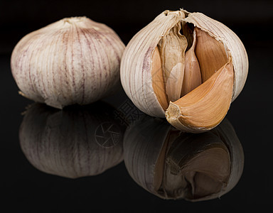 大蒜在壳中 黑色背景上 有反射芳香维生素美食香料灯泡食物丁香洋葱植物收成图片
