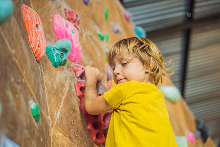 小男孩穿特别靴子在石墙上爬活动爱好闲暇童年男生训练孩子行动运动岩石图片